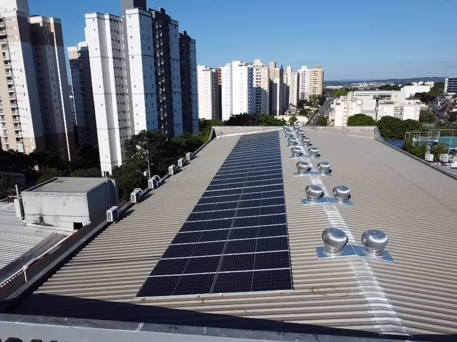 Vista aérea de sistema fotovoltaico instalado em telhado urbano.