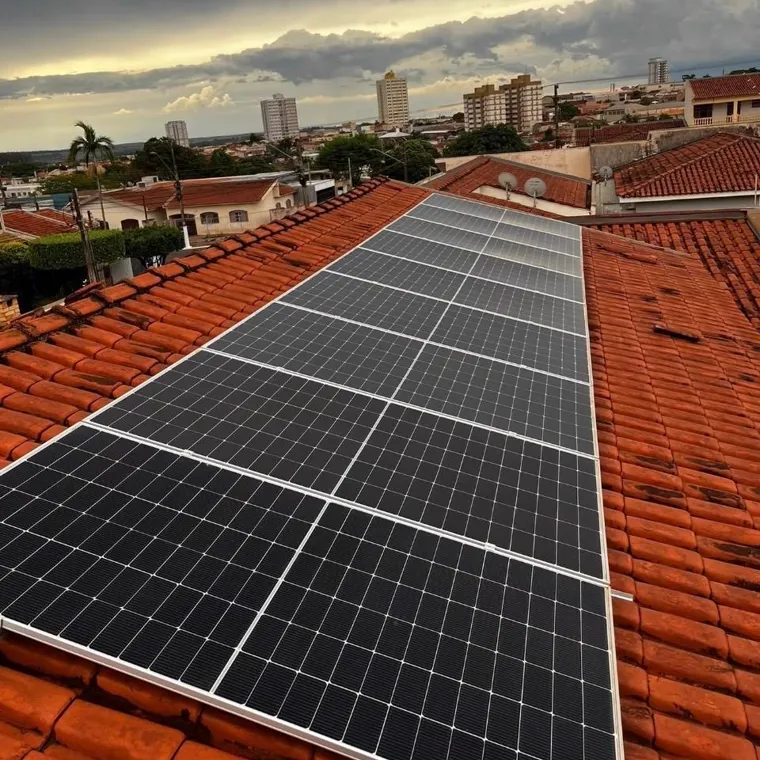 Sistema fotovoltaico instalado em telhado, com a cidade ao fundo.